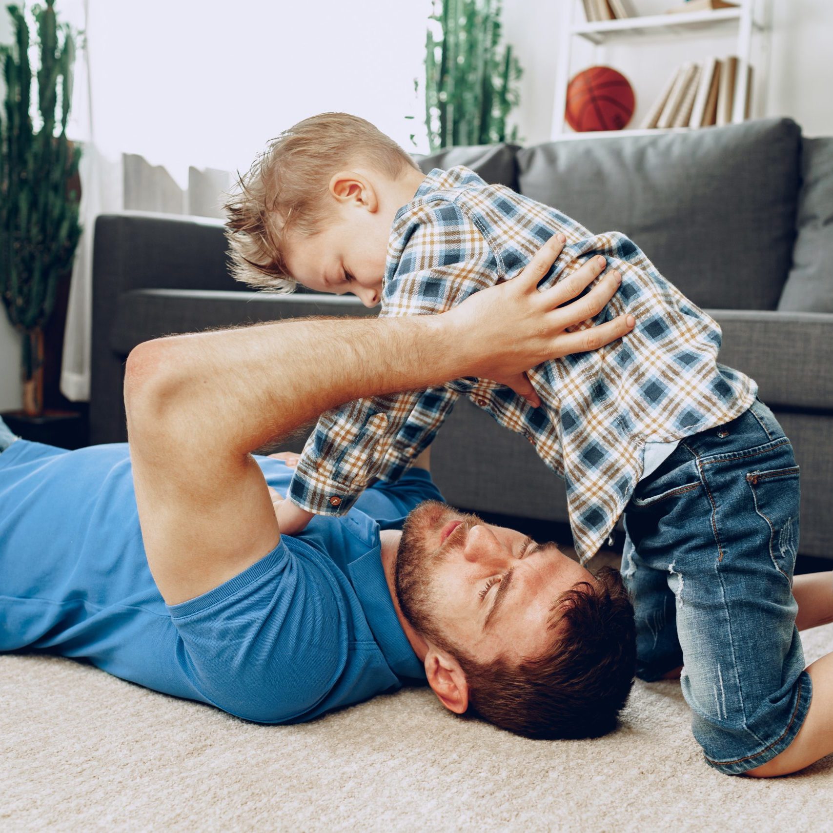 Father and son playing together on carpet at home close up