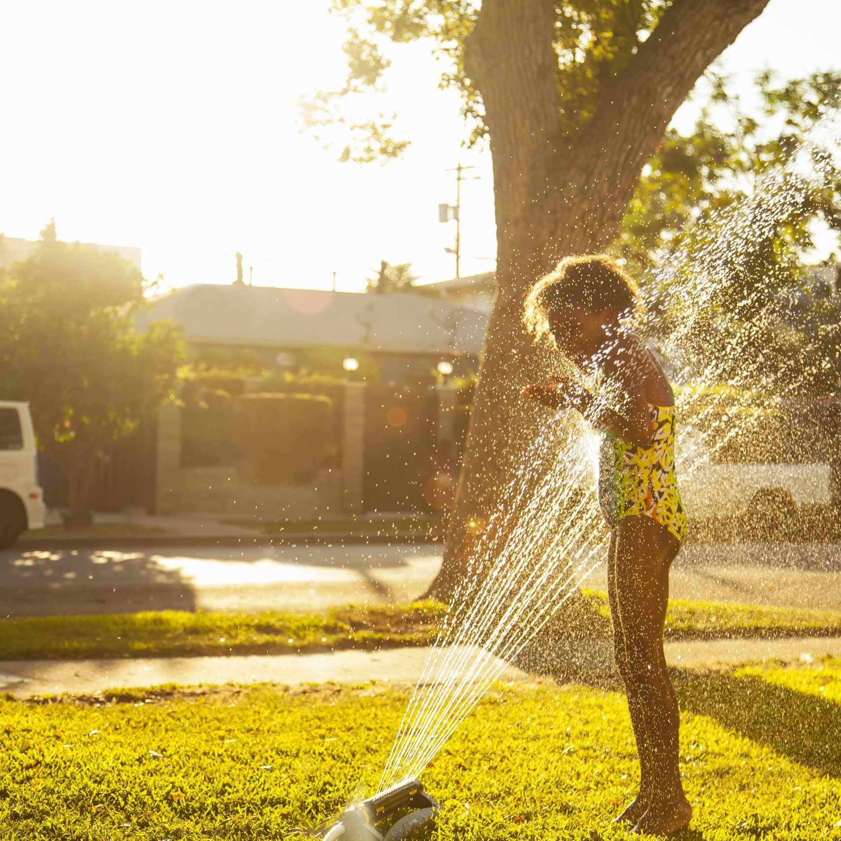 Girl standing in garden sprinkler